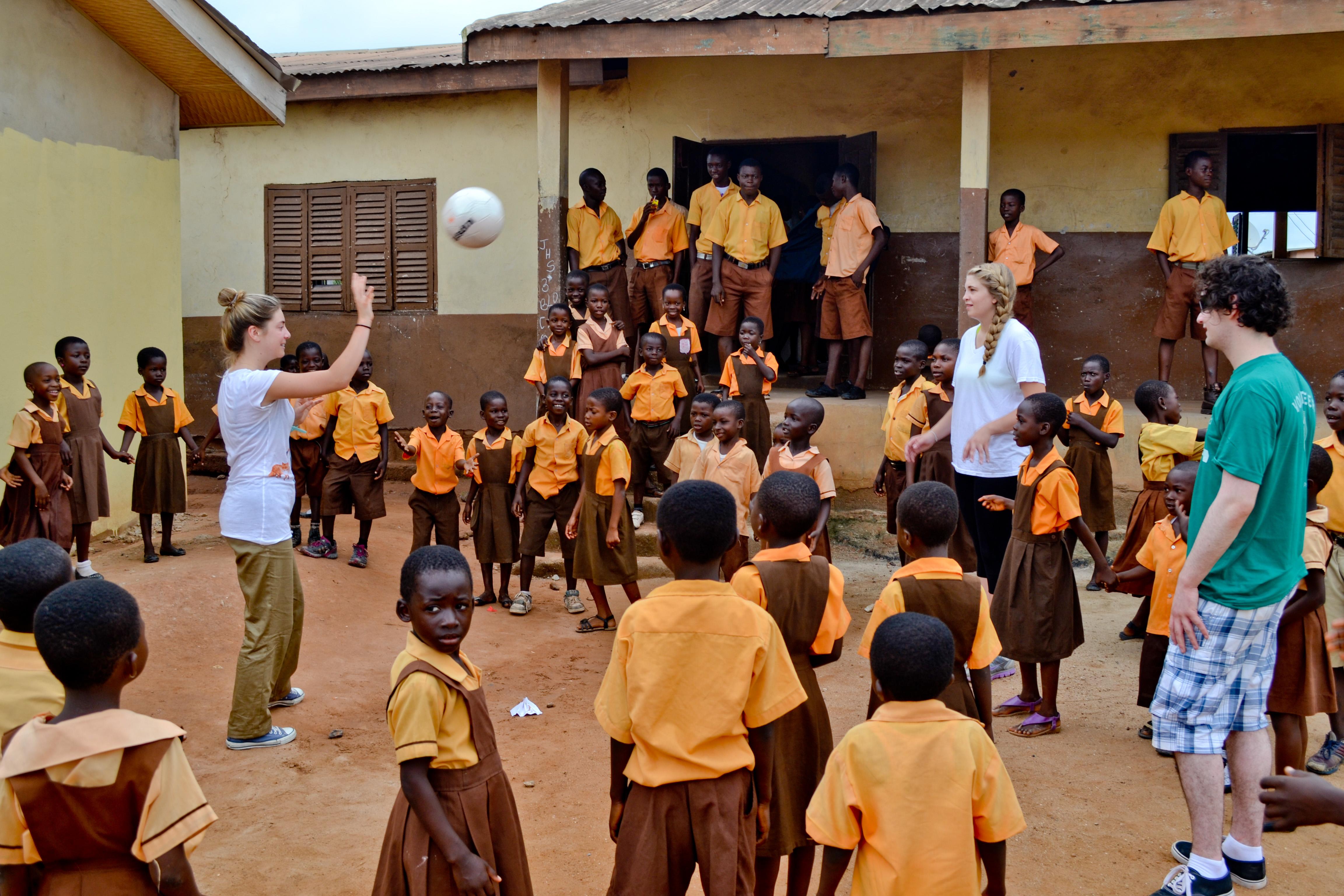 Projects Abroad volunteers play football with their students outside one of the volunteer teaching placements in Ghana Teaching volunteers in Ghana play football in the school courtyard with their students